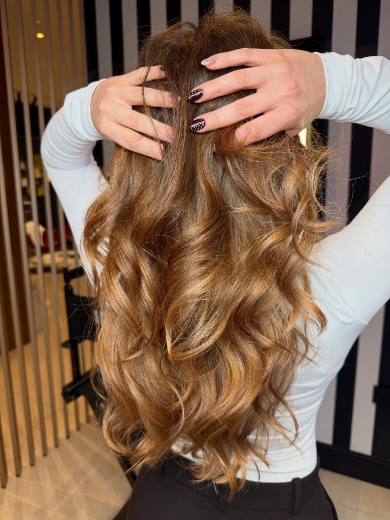 Capelli lunghi mossi con schiariture rame dorate realizzate da LEAH Atelier Hair & Beauty